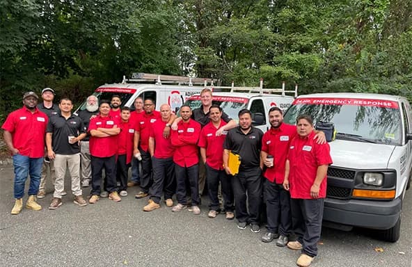 Advanced DRI restoration team standing in front of emergency response vehicles